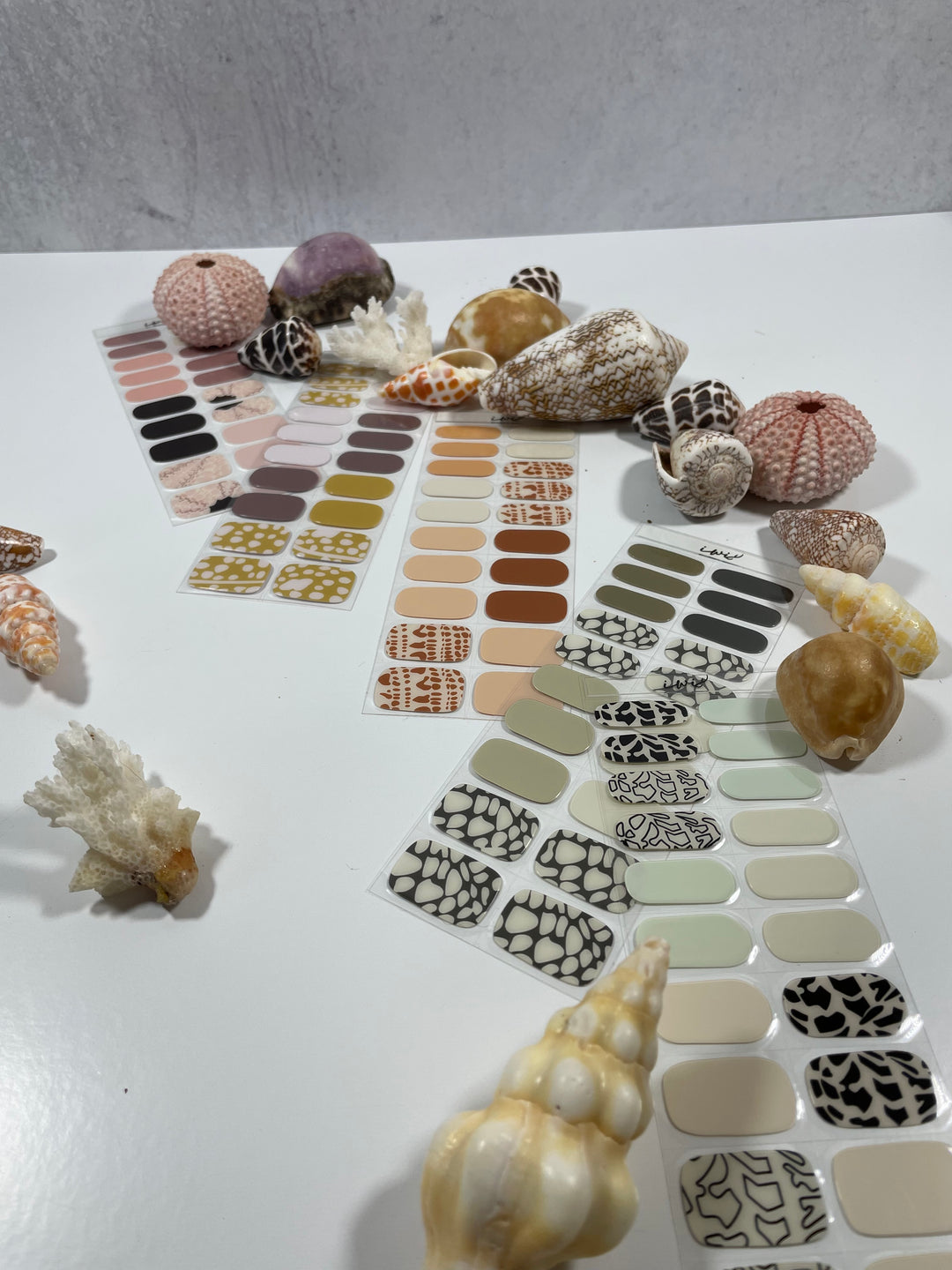 A collection of semi cured gel nail strips with various shell  and beachy patterns